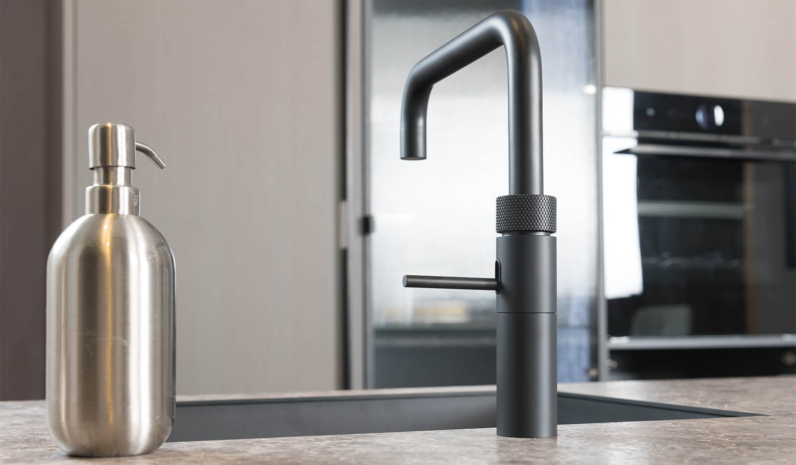 Grijze keuken met zwarte apparatuur en grepen